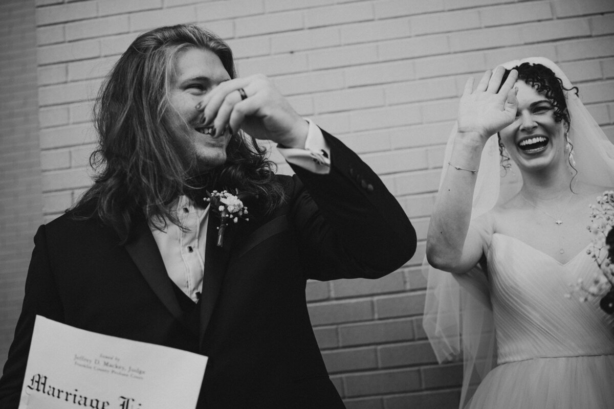 Couple laugh and wave as they just eloped in the city