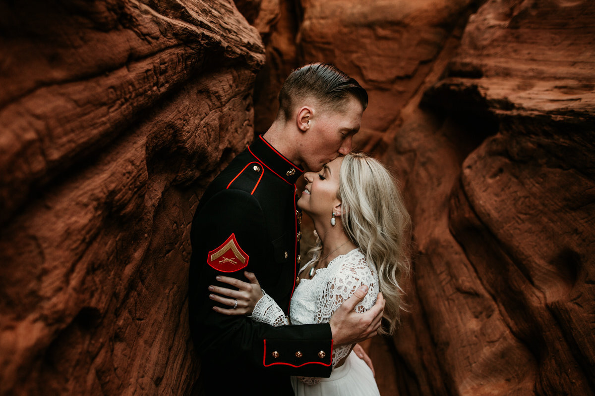 groom kissing wife's head in a red rock canyon