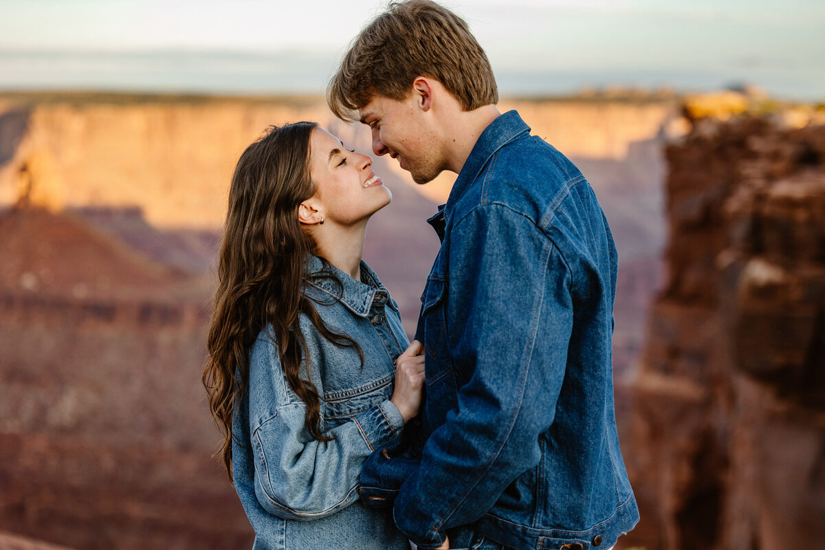 A bride and groom touch noses during their sunrise elopement session in Moab