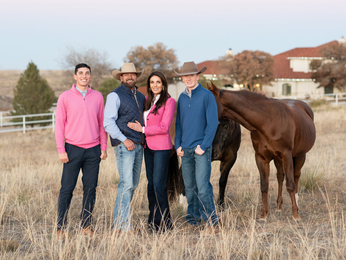 Family of 4 with their two horses for their family pictures in a grassy field