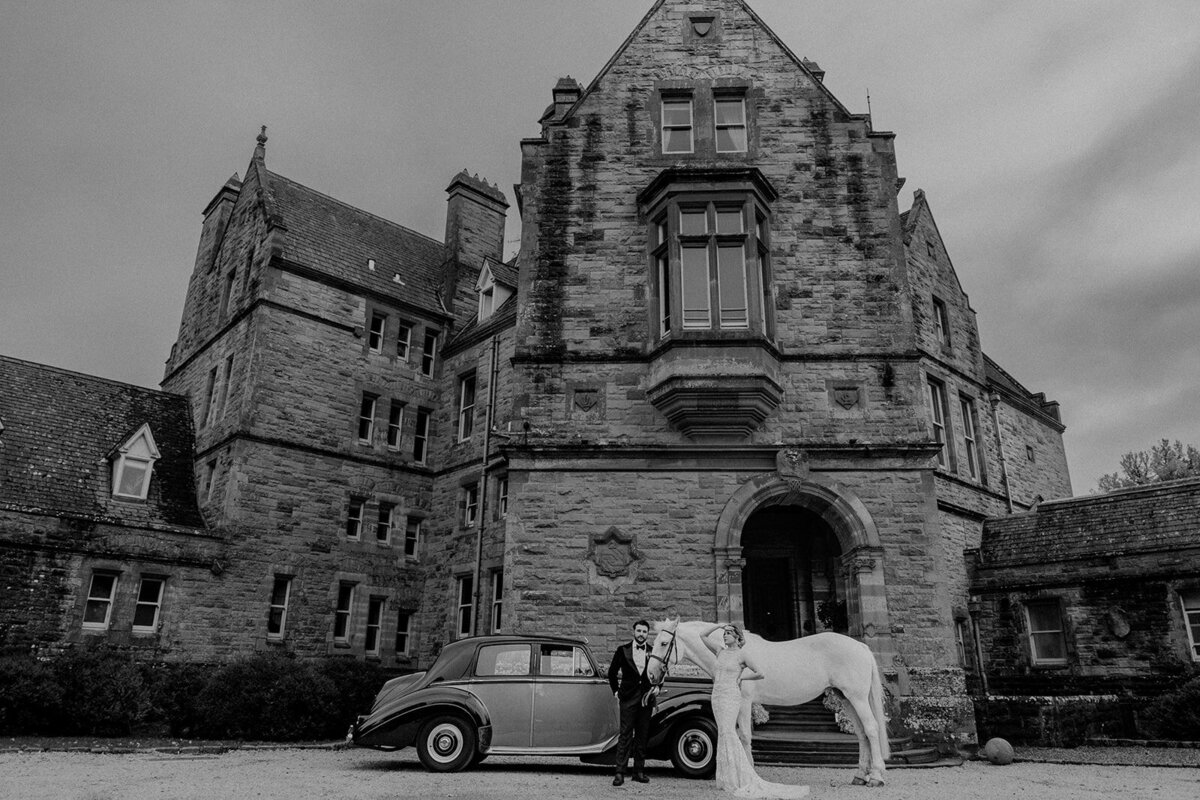 Bride and groom posing with horse and car in front of Ireland castle
