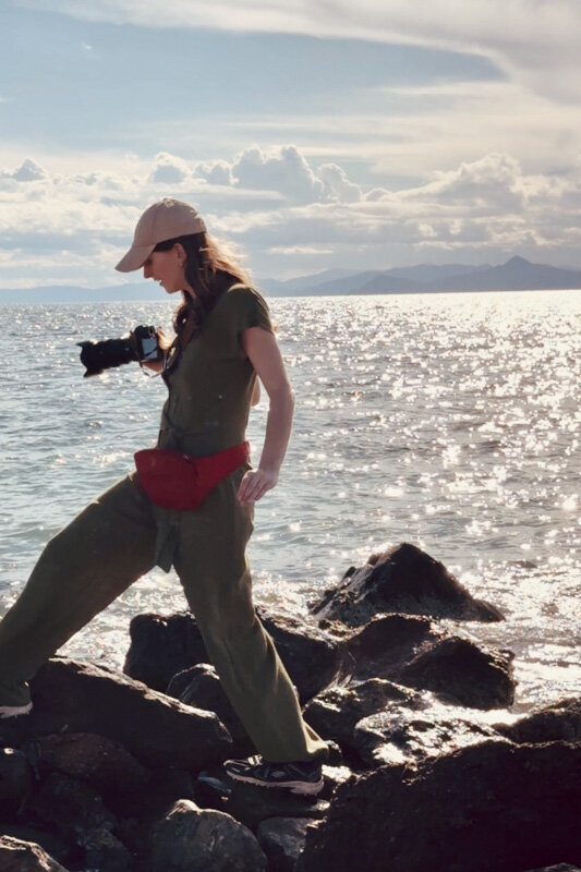 Female walking on a beach and holding a camera