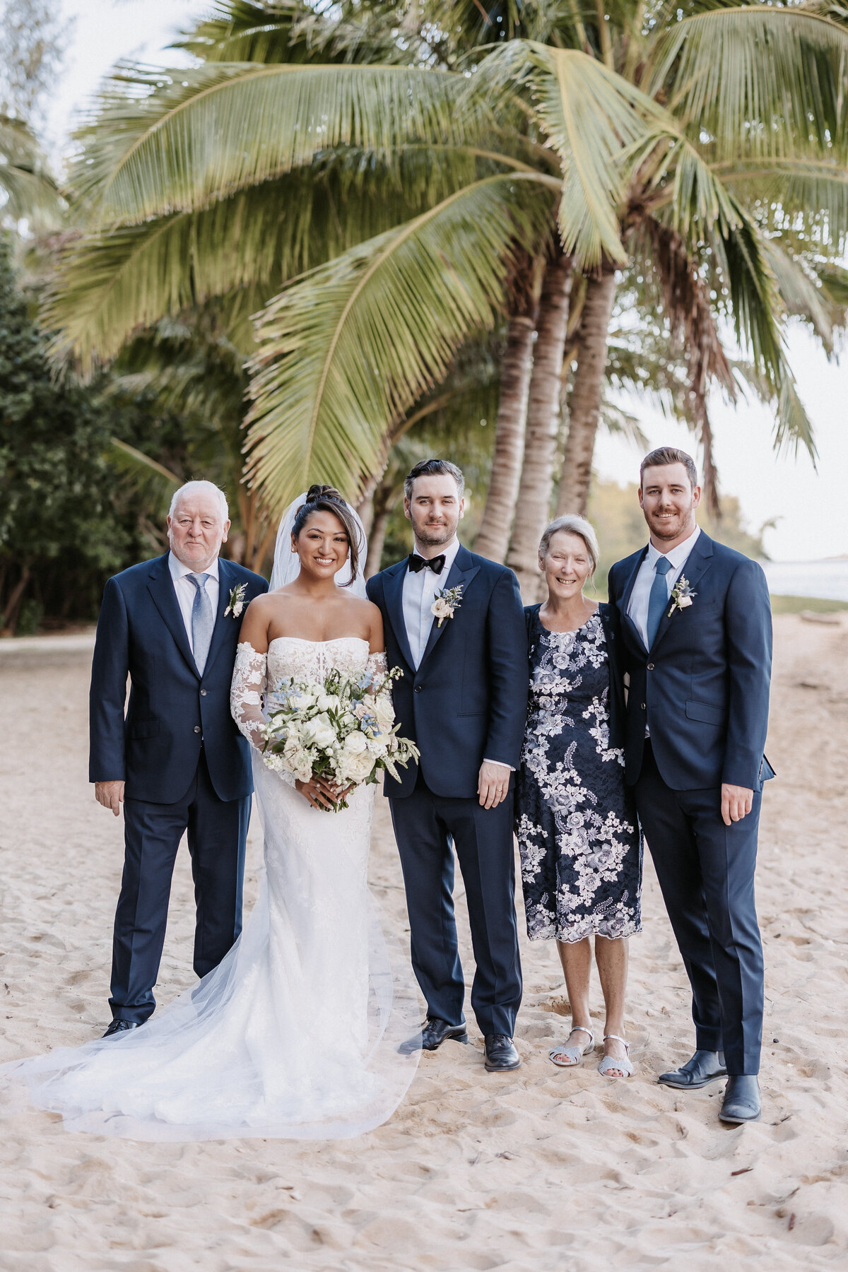 Family photo on Secret Island beach wearing navy blue colors and palm trees in the background
