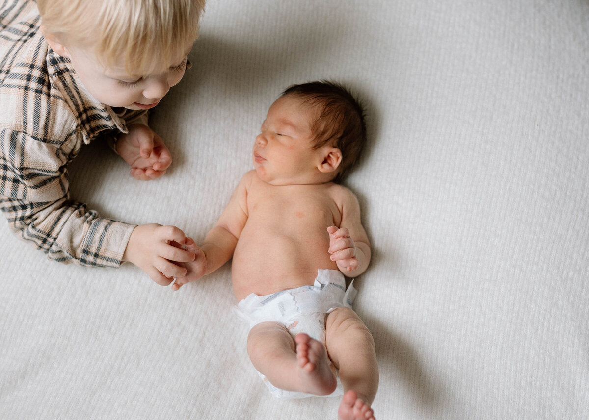 Parents sitting on bed with baby during calm, intentional newborn session