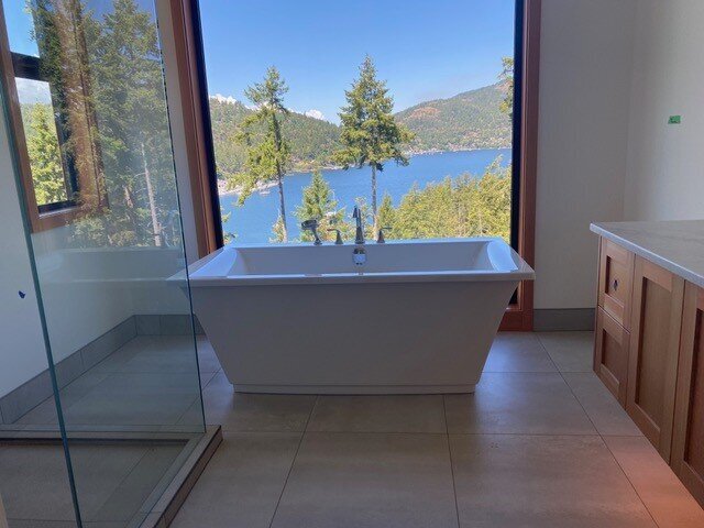 Bathroom interior design with freestanding soaker bathtub overlooking water view.