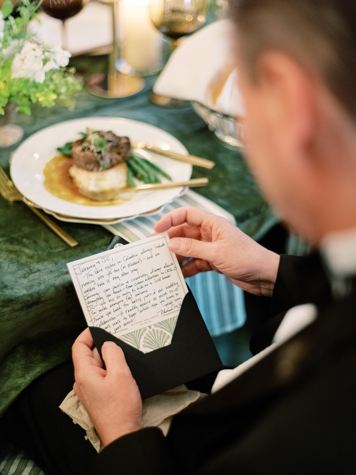 A guest reads a heartfelt note during the wedding dinner, bringing a moment of reflection and warmth to the gathering, surrounded by guests enjoying the dining experience.