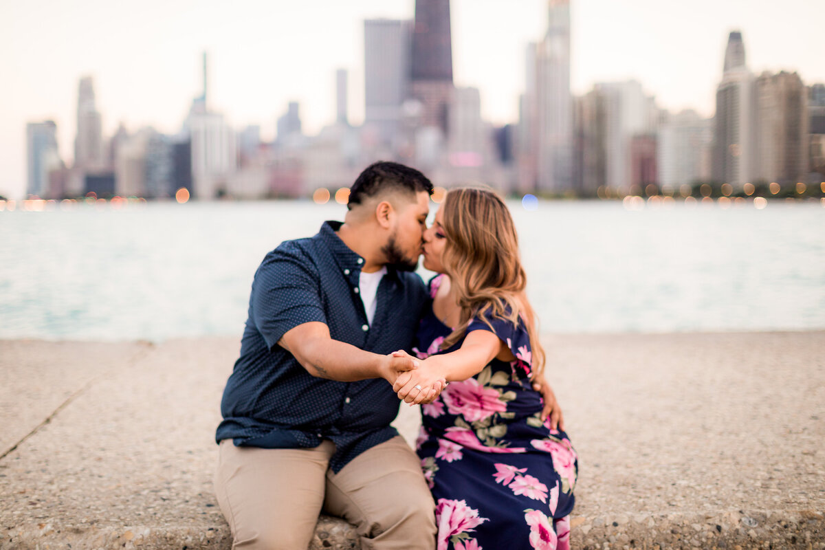 Marisela and Rigo share a kiss at North ave beach in front of the sky line.