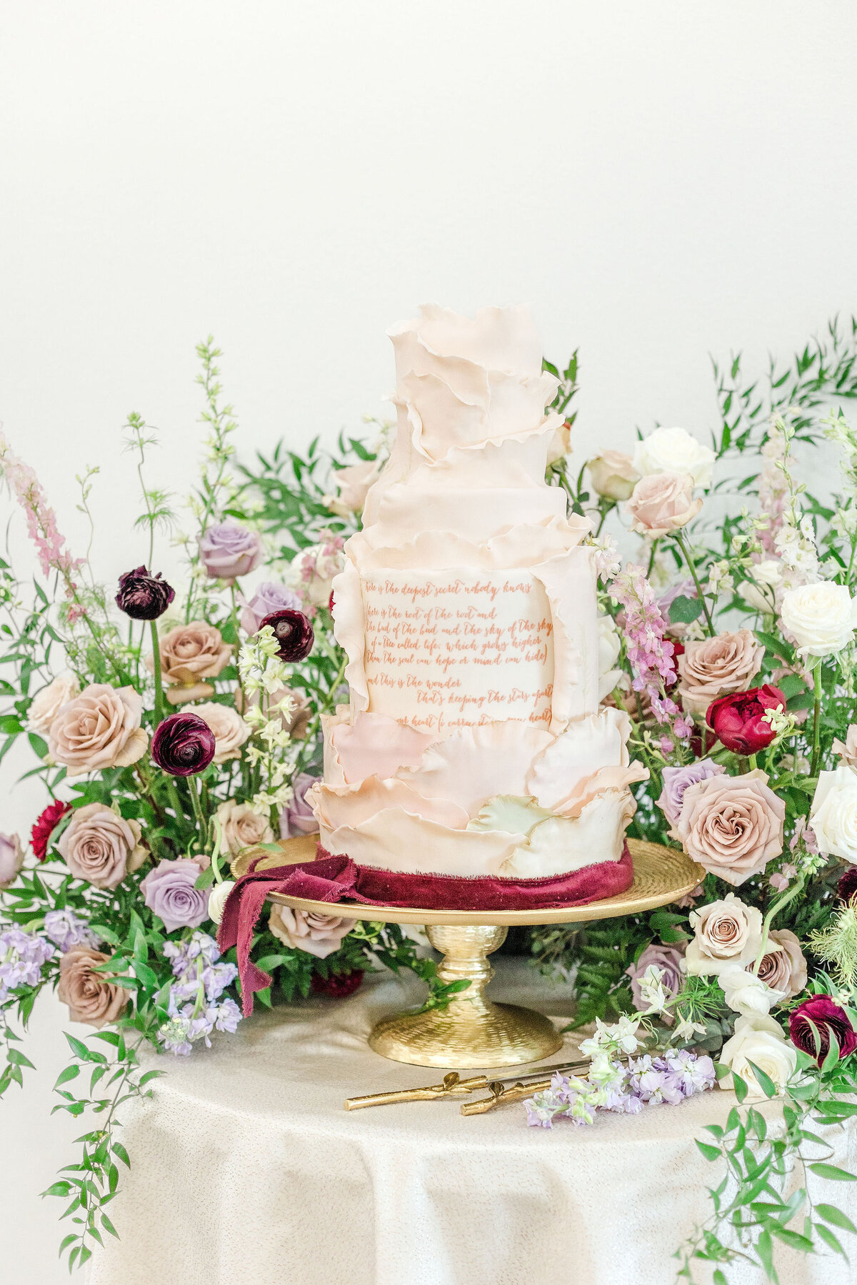 A beautifully designed luxury wedding cake surrounded by fresh floral arrangements, perfect for elegant celebrations at Willow and Stone Events in Mocksville, NC.