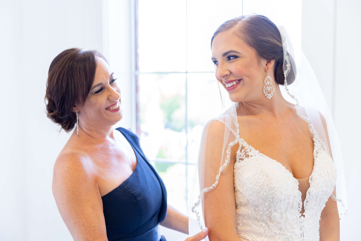 Bride looking around at mother as she fixes her dress