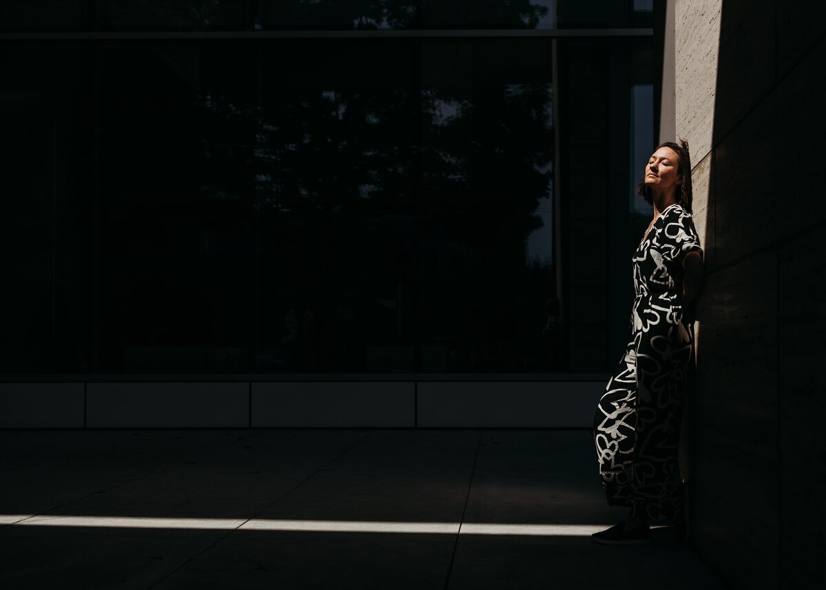 portrait of woman standing in ray of light downtown