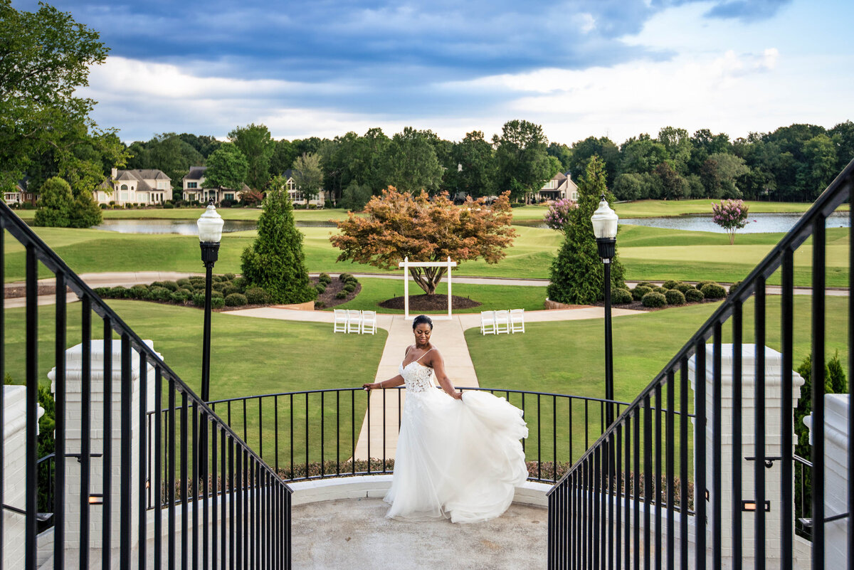 Bridal portrait of bride dancing  on steps at Providence Country Club with view of golf course by Charlotte wedding photographers DeLong Photography