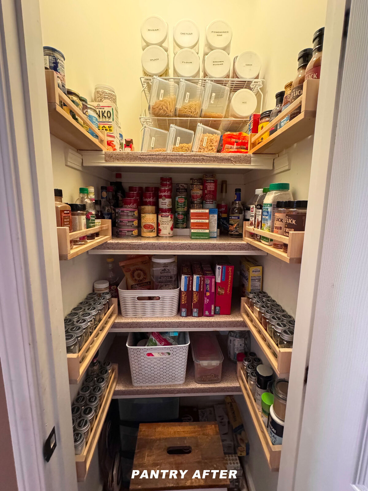 A well-organized pantry with labeled shelves and containers. Items include jars, boxes, and bottles neatly arranged. Clear bins hold pasta and other goods. A wooden crate is on the floor. Text at the bottom reads "PANTRY AFTER.