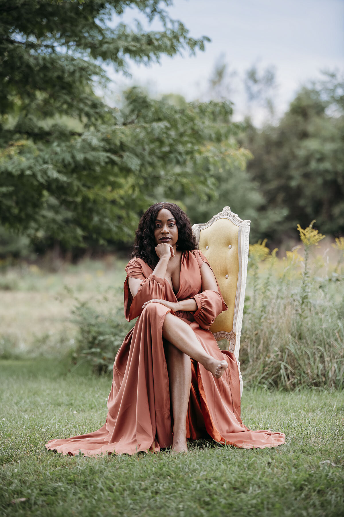 woman wearing a rose colored dress sitting in a field