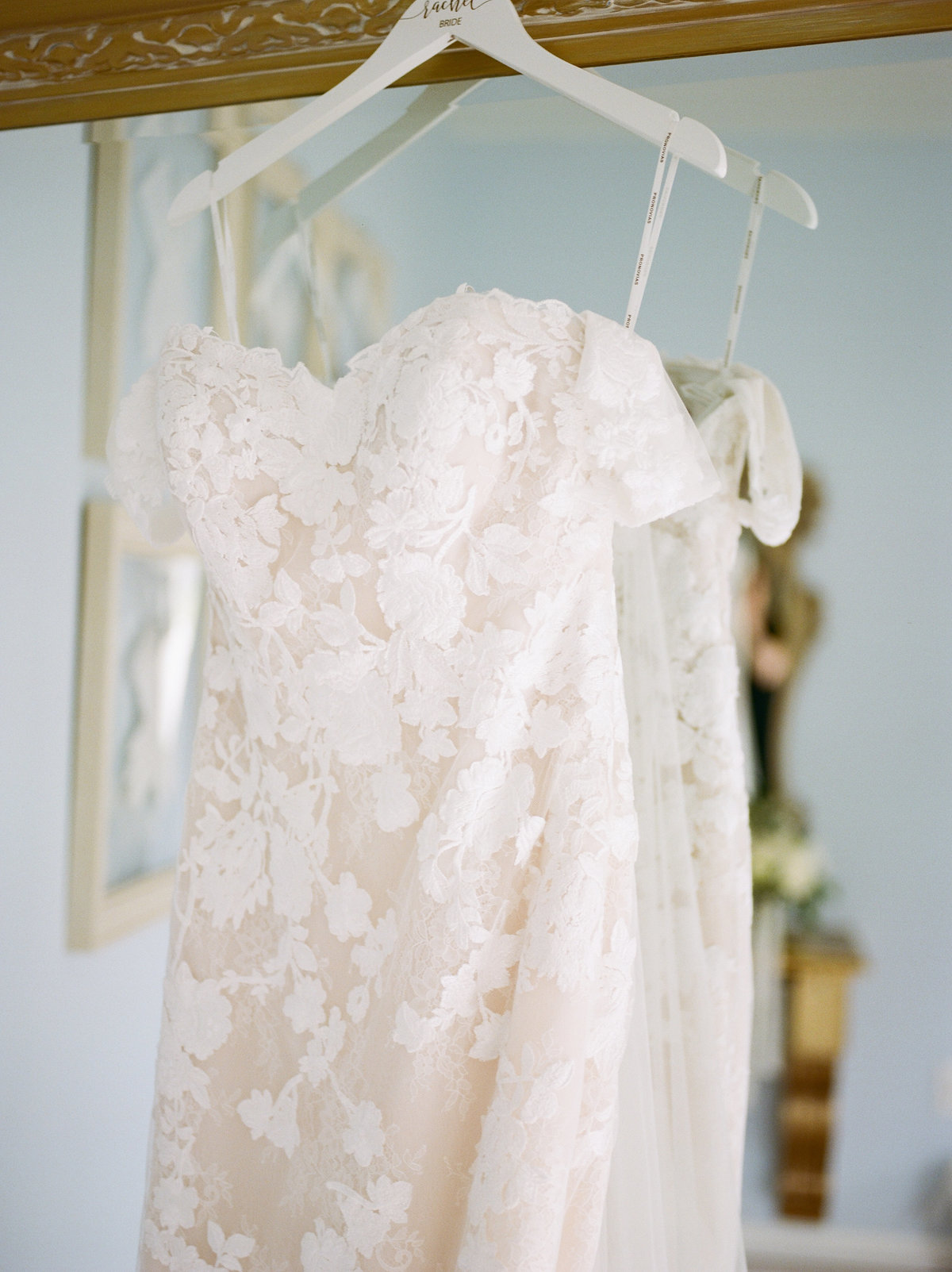 lace strapless wedding gown hanging on mirror