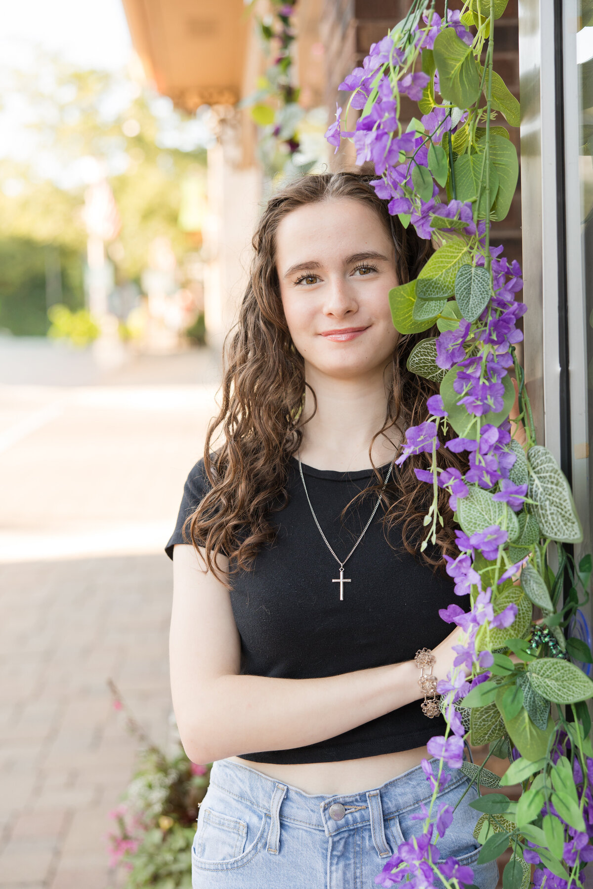 Senior girl standing amongst flowers and smiling at the camera