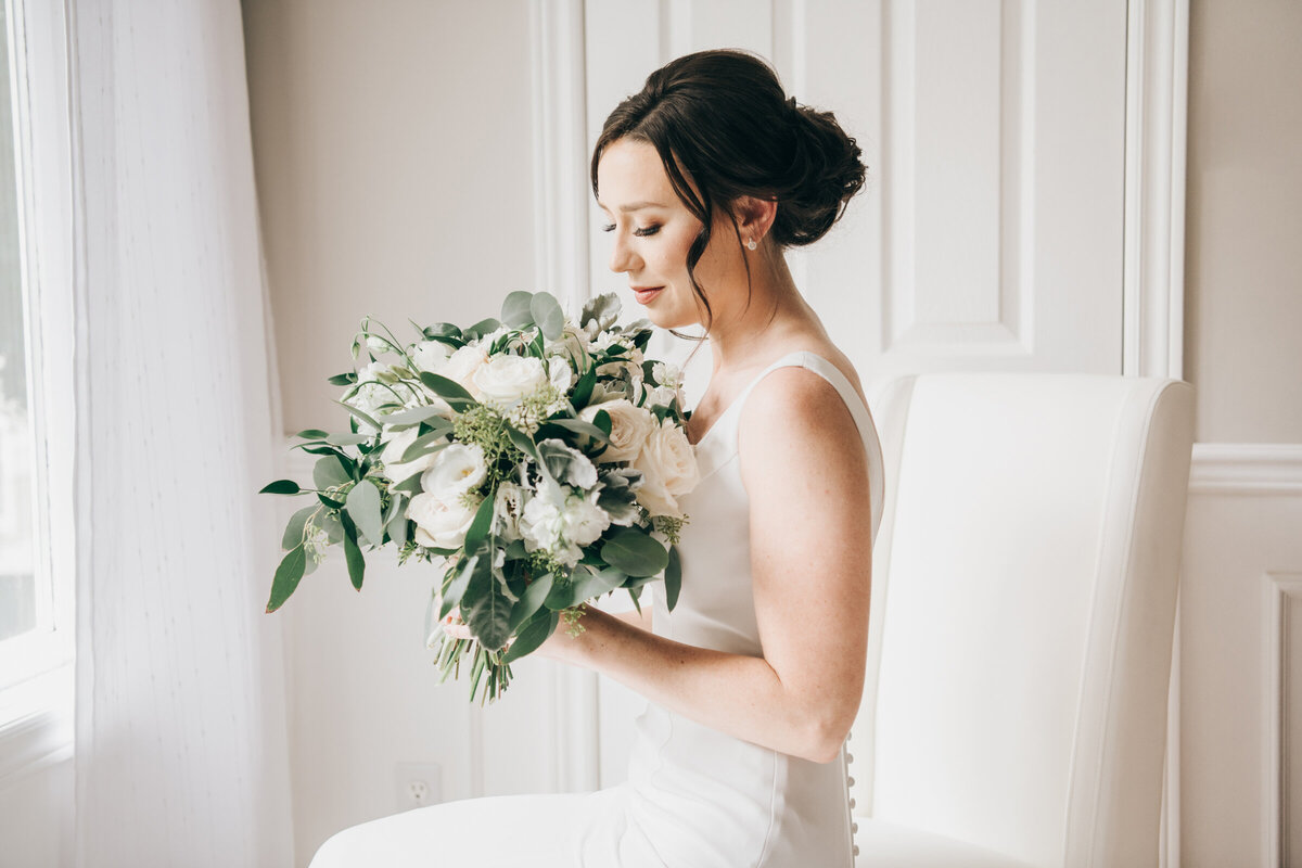 An elegant bride sitting with her gorgeous white wedding bouquet