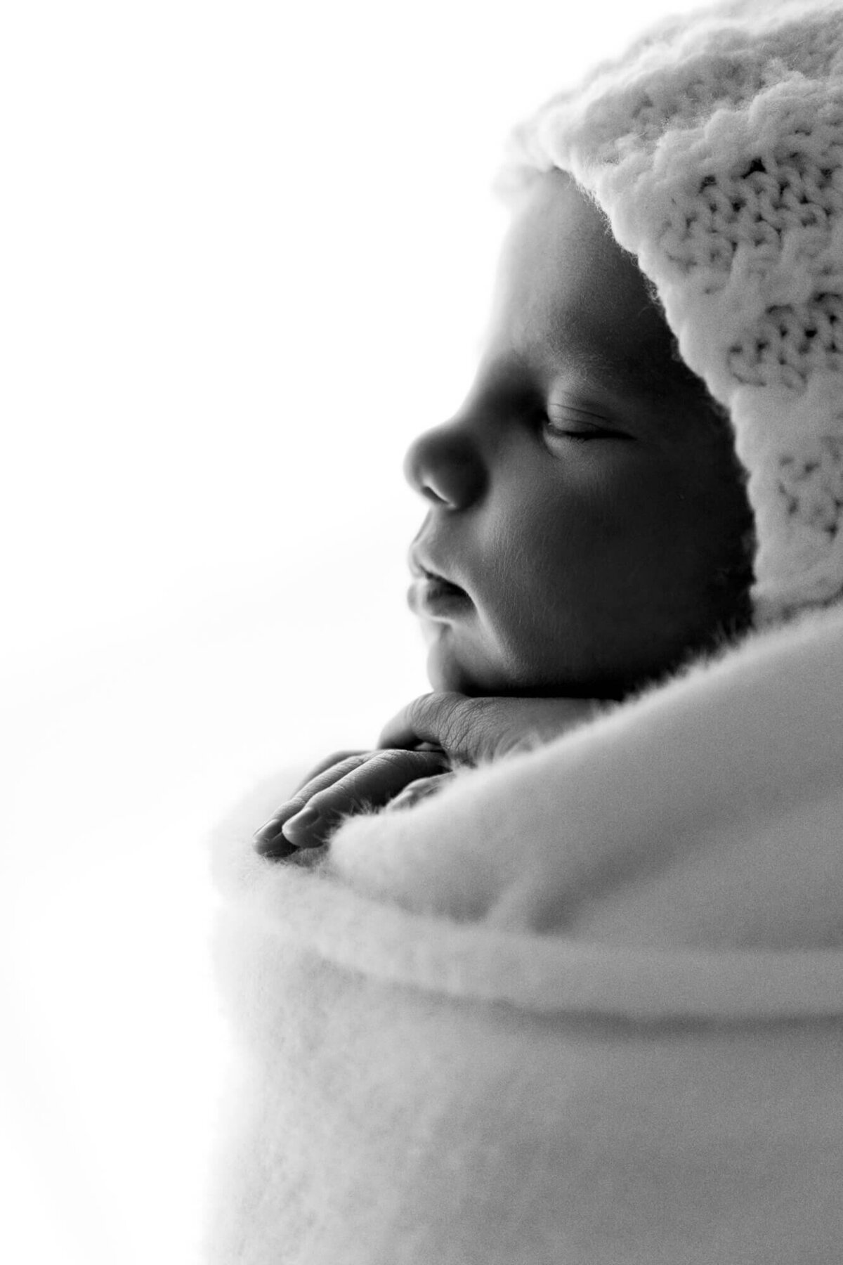 Black and white profile photo of a one week old baby girl wearing a bonnet, Oklahoma newborn photographer.