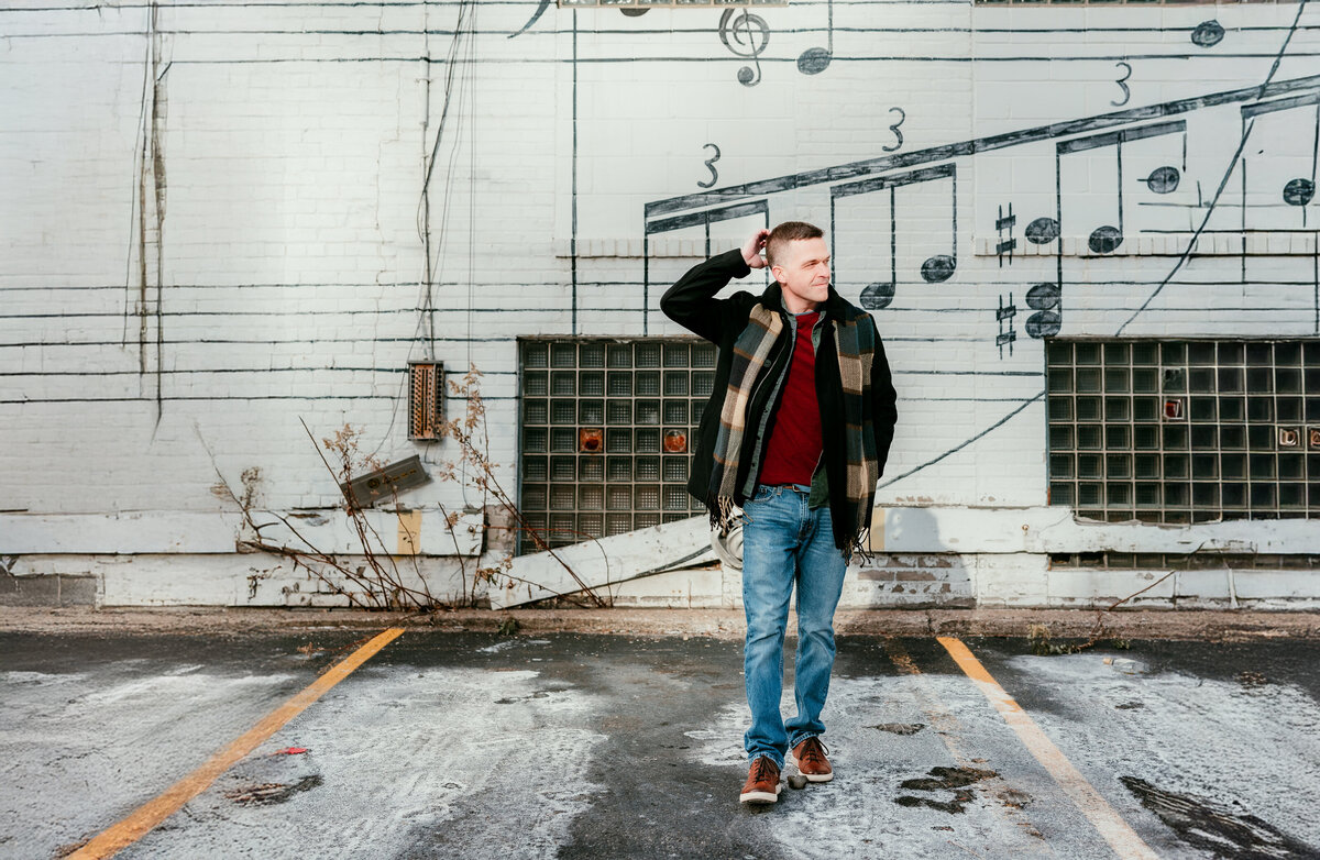 Man standing confidently in a modern urban setting, wearing a jacket and jeans, perfect for a standout dating profile photo.
