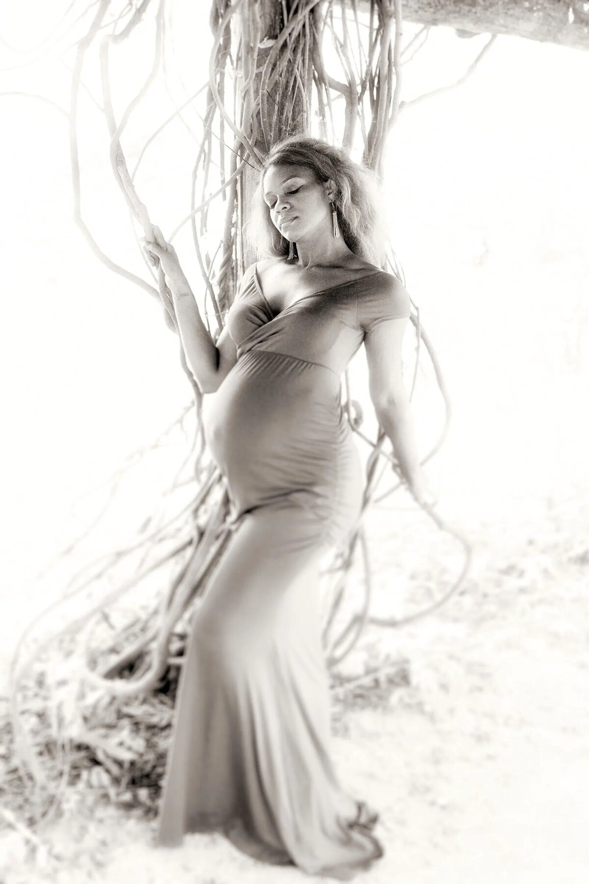 Black and white photo of a pregnant woman in a long dress.