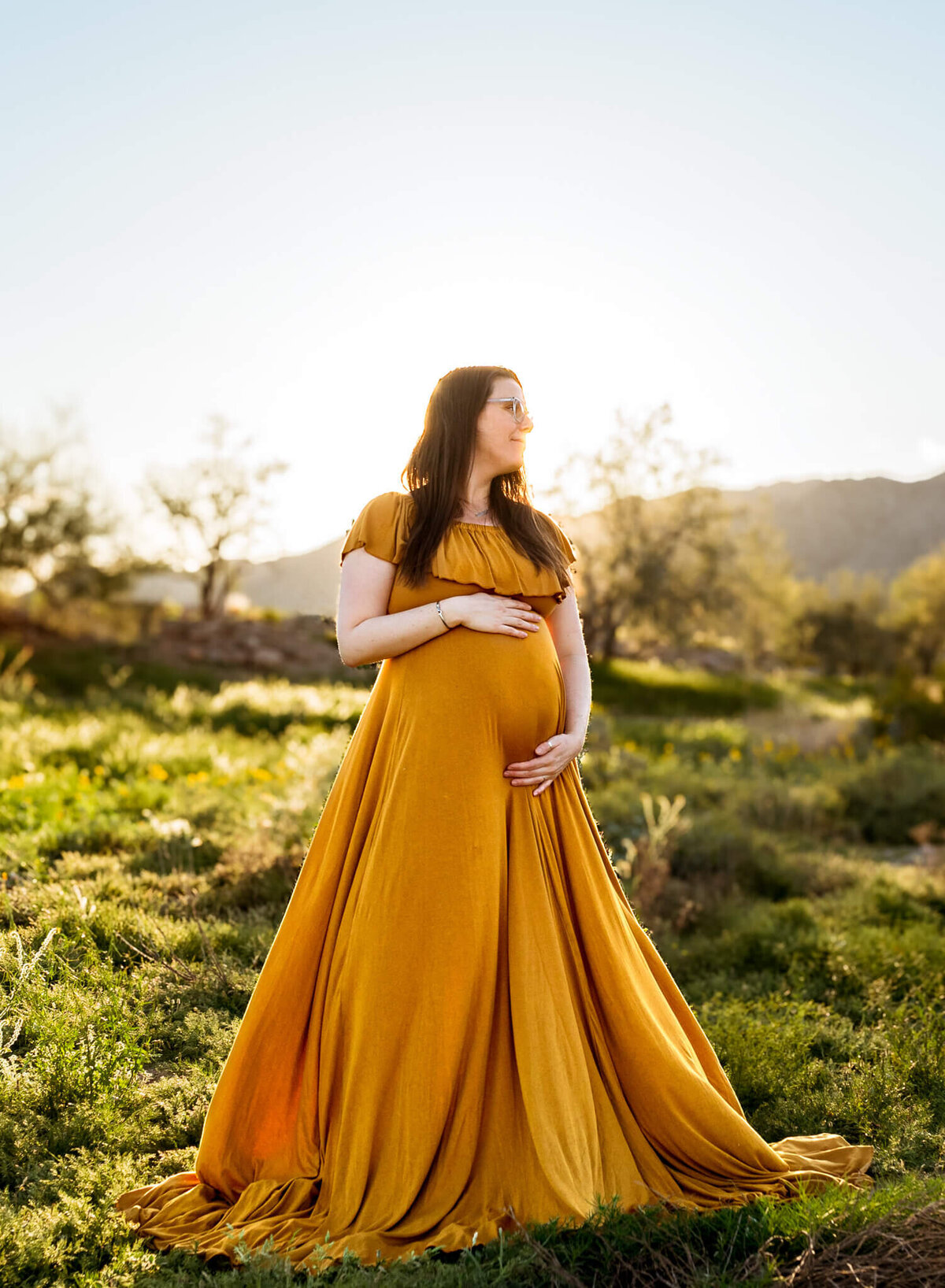 mother-to-be holding her baby bump in a lush Arizona desert. Photographed by Cactus & Pine Photography