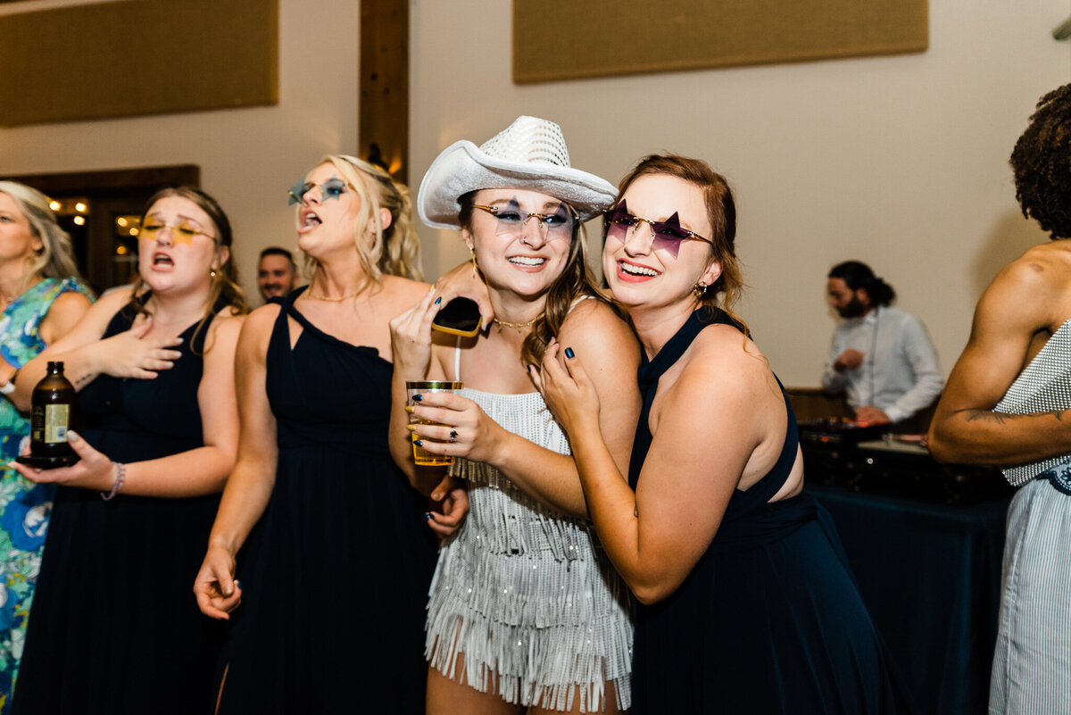 wedding reception pictures of bride with her bridesmaids drinking and dancing together with star glasses on