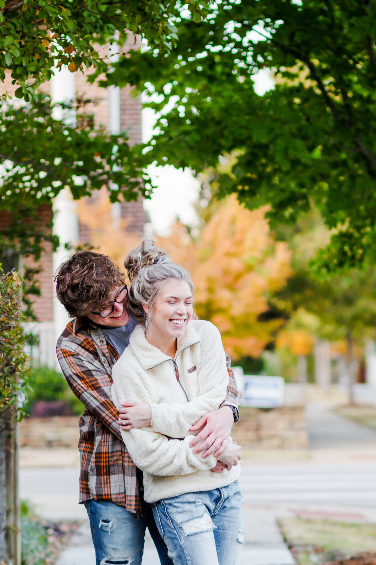 A guy and girl laugh at each other while standing on a sidewalk in Conway, Ar.