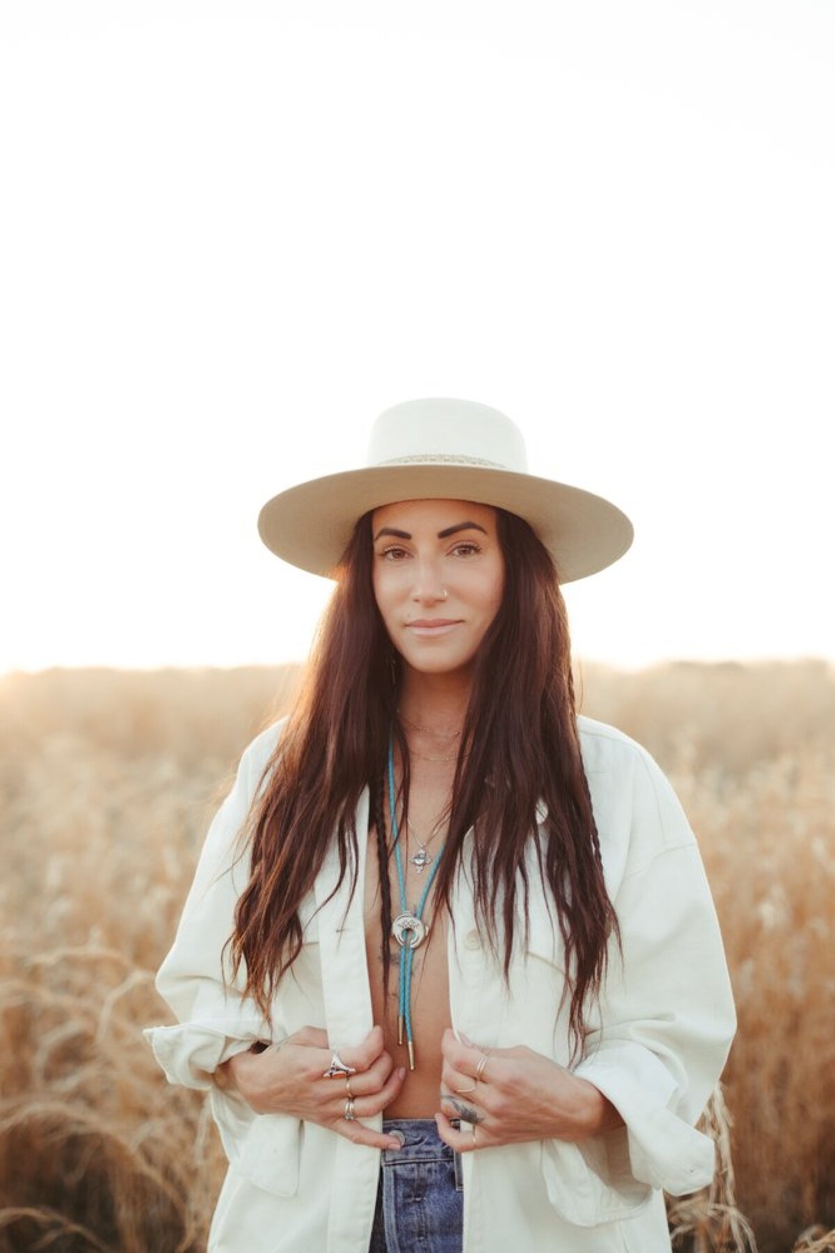 woman-in-hat-standing-in-field-at-sunset