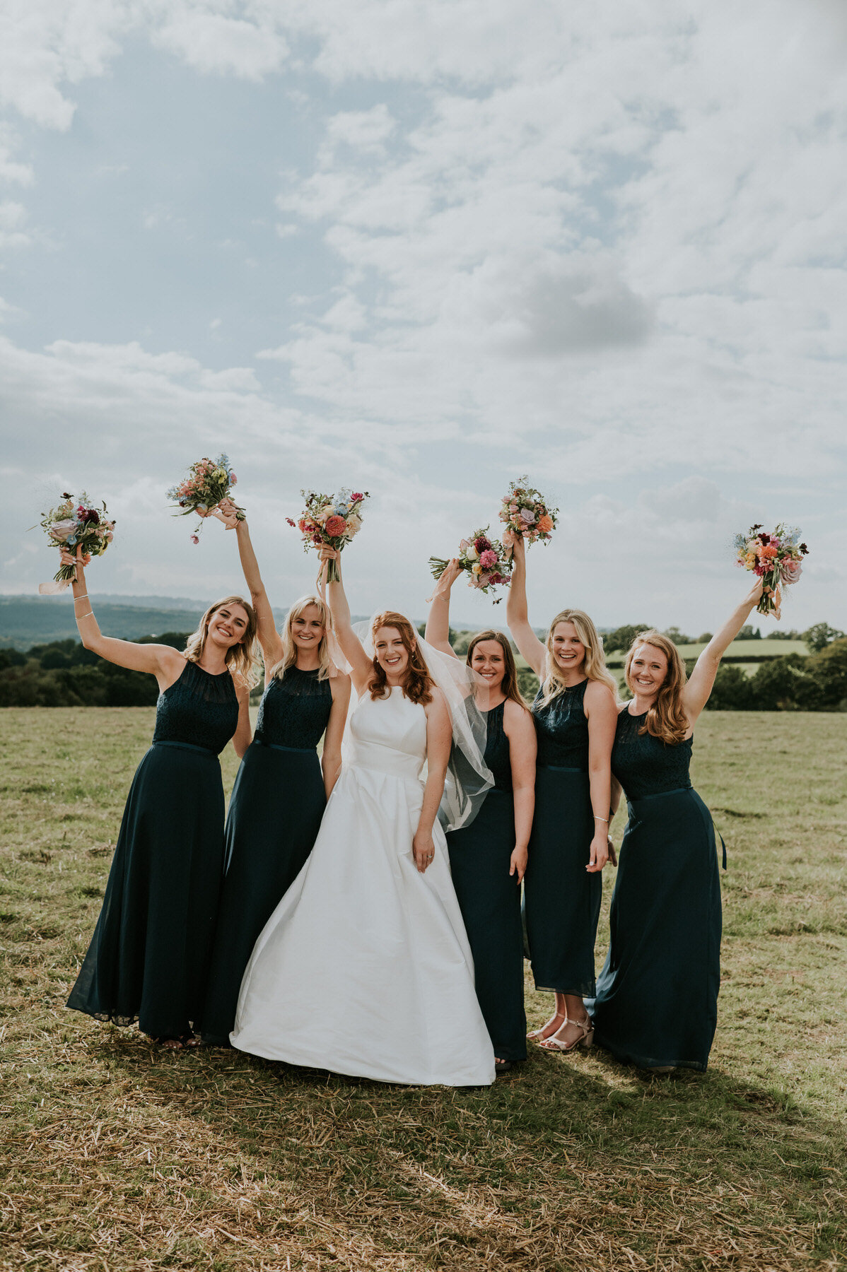 Bride and bridesmaids waving bouquets in air