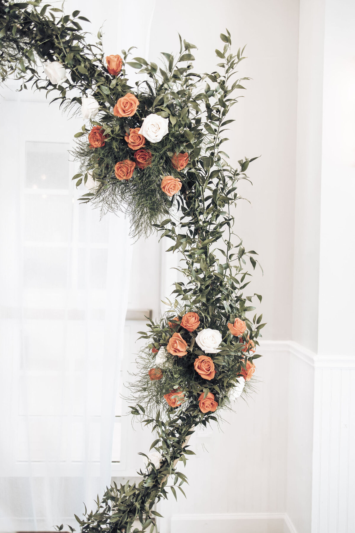flower arch with orange and white roses and greenery
