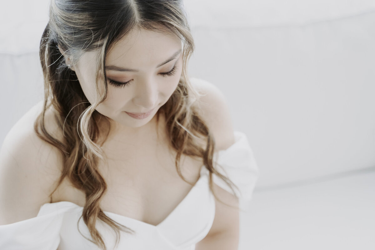 the bride with her make up and hair wearing an off shoulder wedding dress