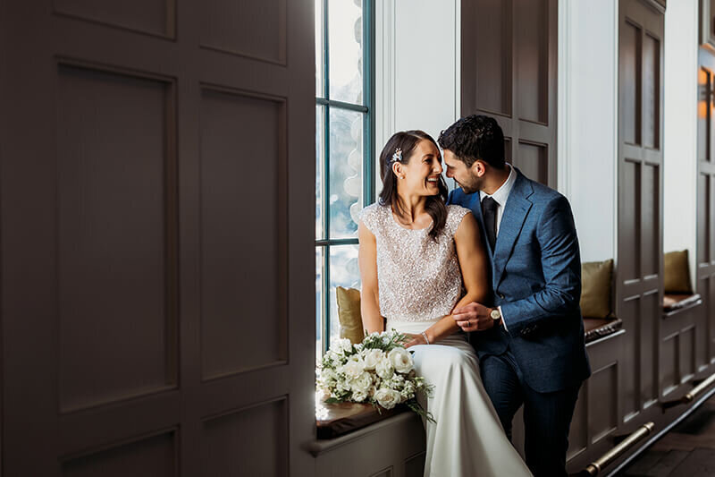 Husband and wife snuggle and kiss in window light at the Surf Hotel in Buena Vista
