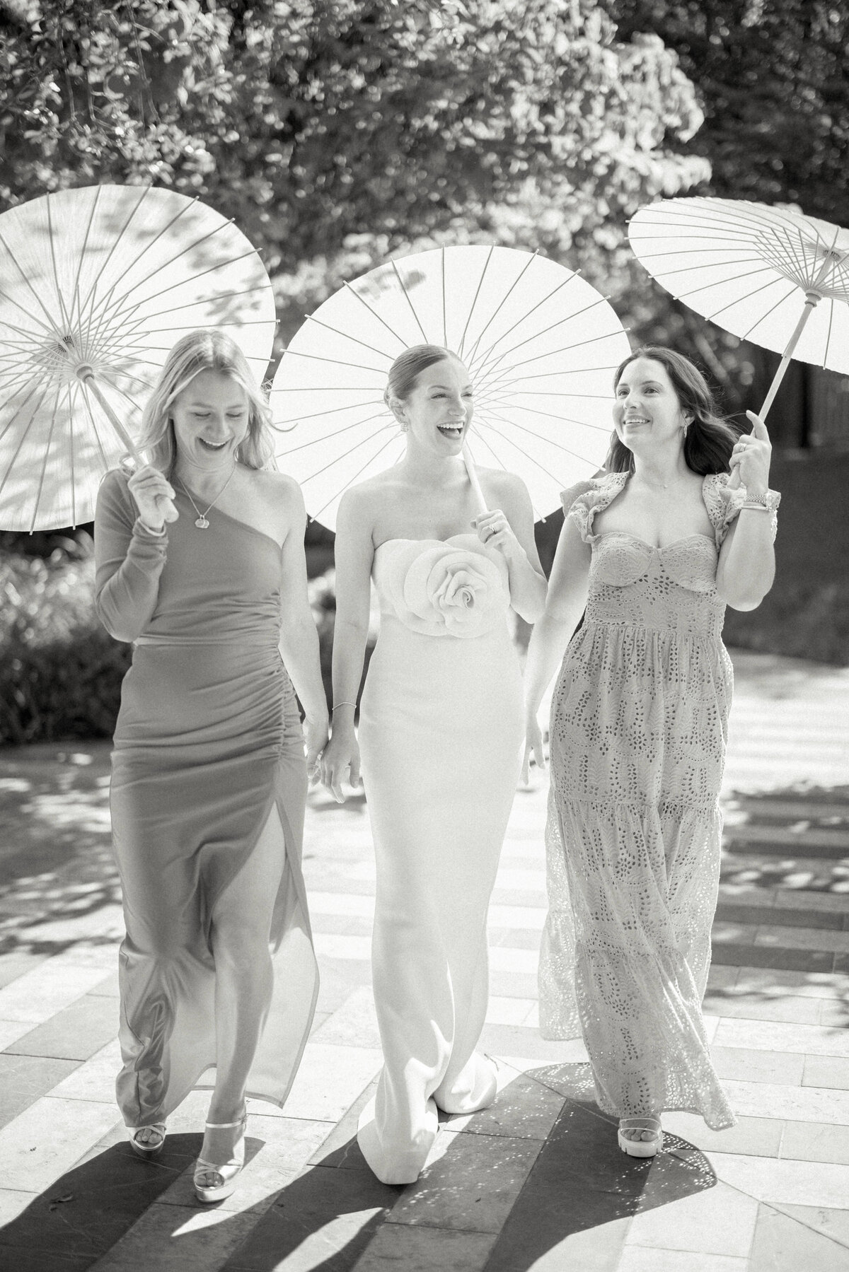 three women walking with parasols at wedding