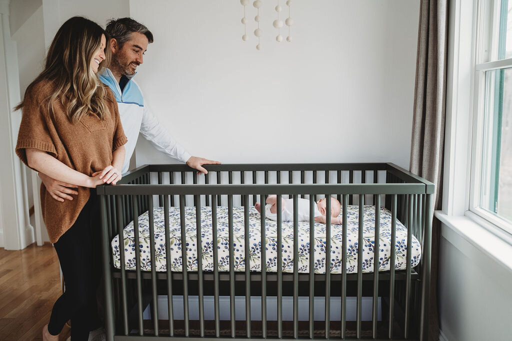 new parents watching over their baby in her boston nursery