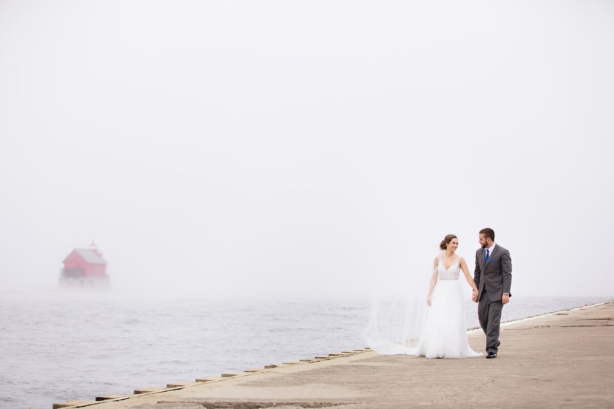 Bride and groom walking the pier on Lake Michigan in Grand Haven.