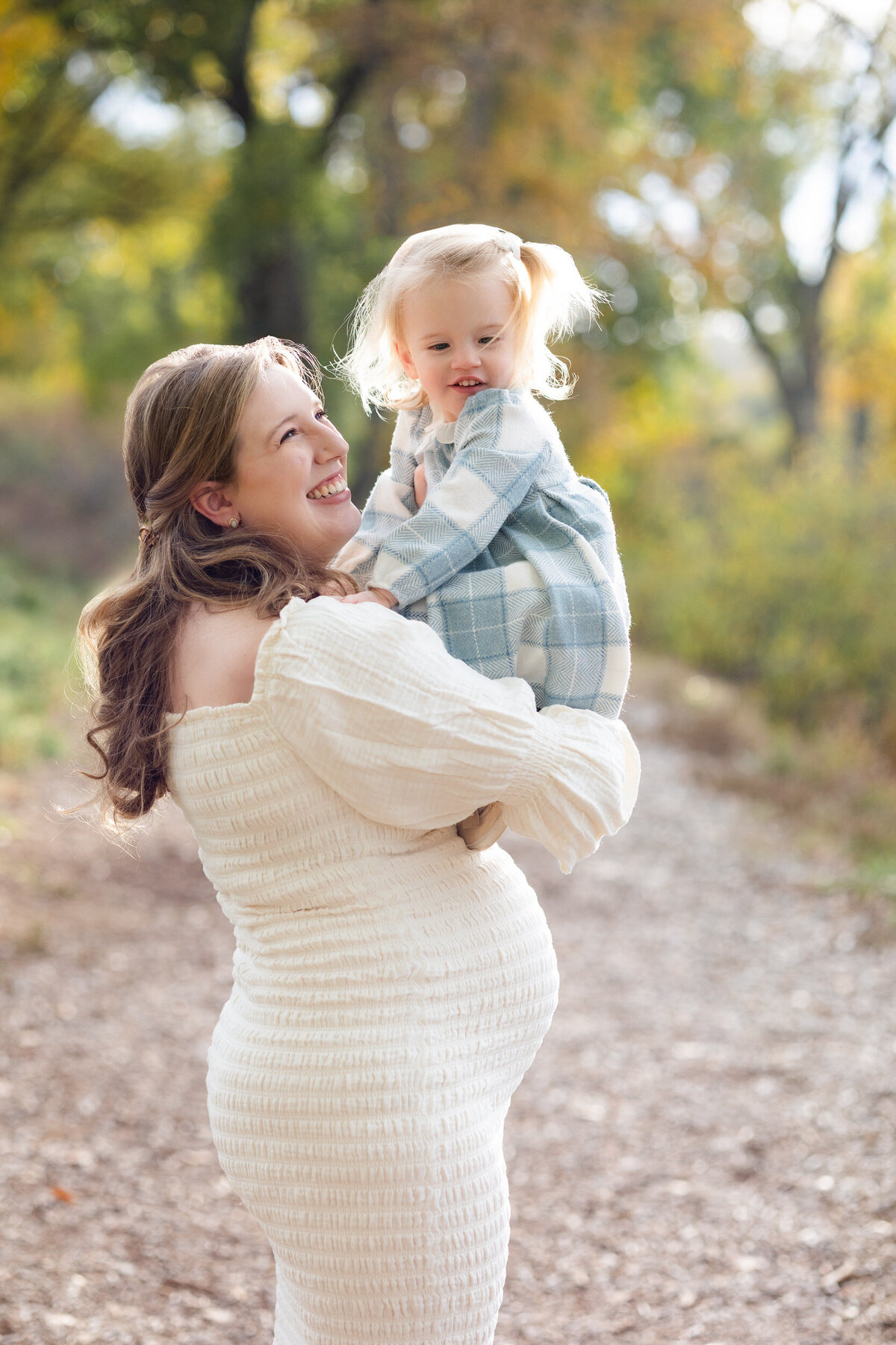 Mom holds toddler daughter and smiles at her.