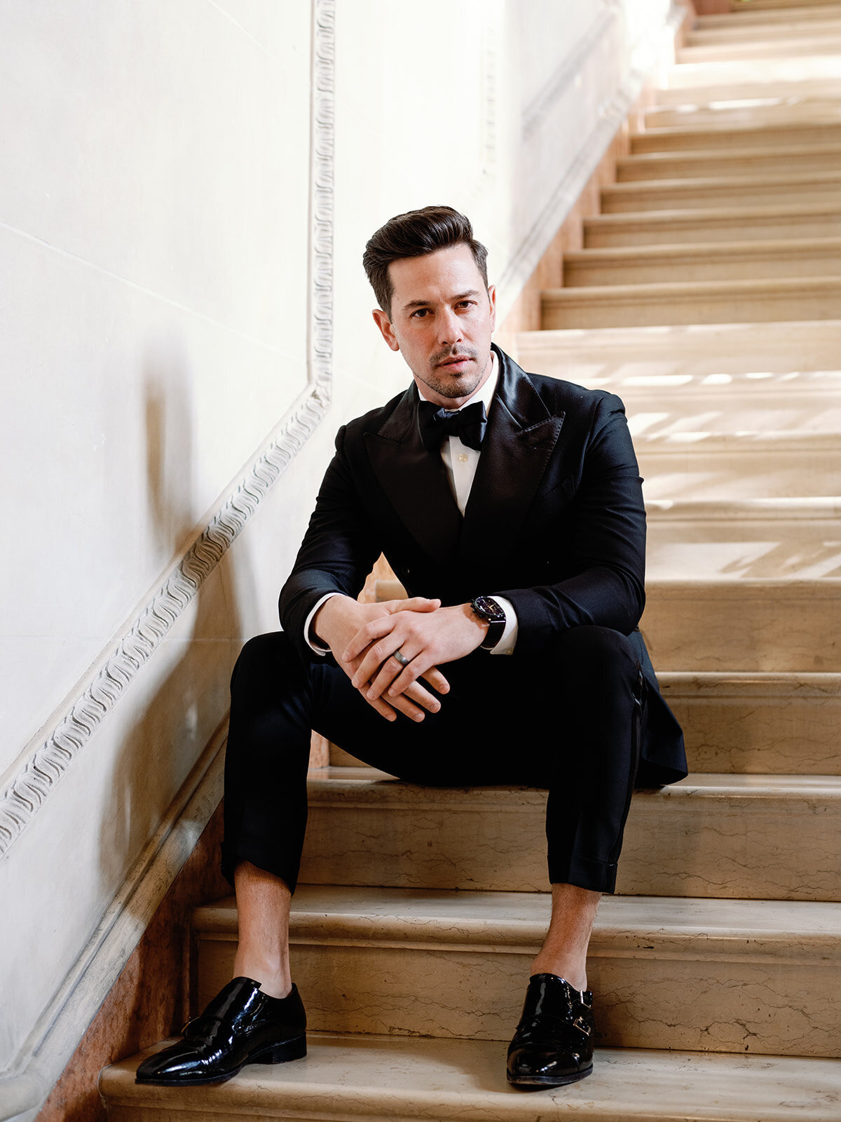 A groom sits on the steps of Larz Anderson house steps.