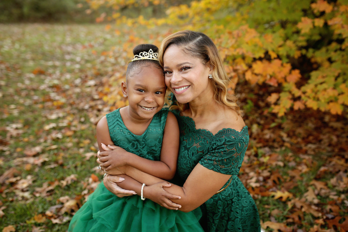 mother and daughter in formal green dresses posed closely  fall outdoors