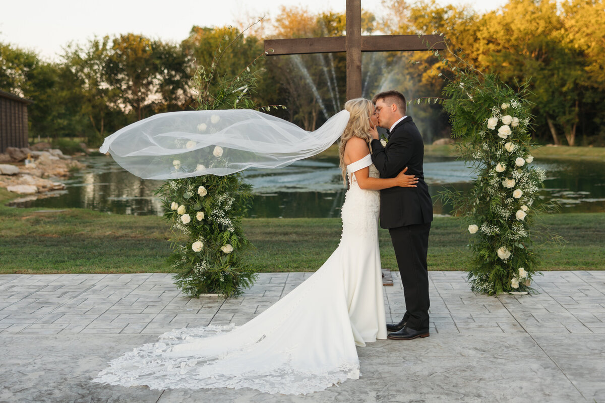 bride and groom kissing in front of a wooden cross
