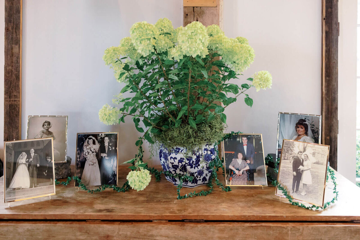 Photos of the couple's parents' weddings and a beautiful flower centerpiece are on a wooden table at The Lion Rock Farm, CT.