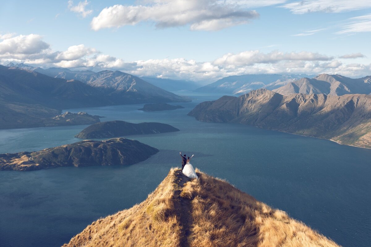 A couple photographed on a mountain overlooking Lake Wanaka