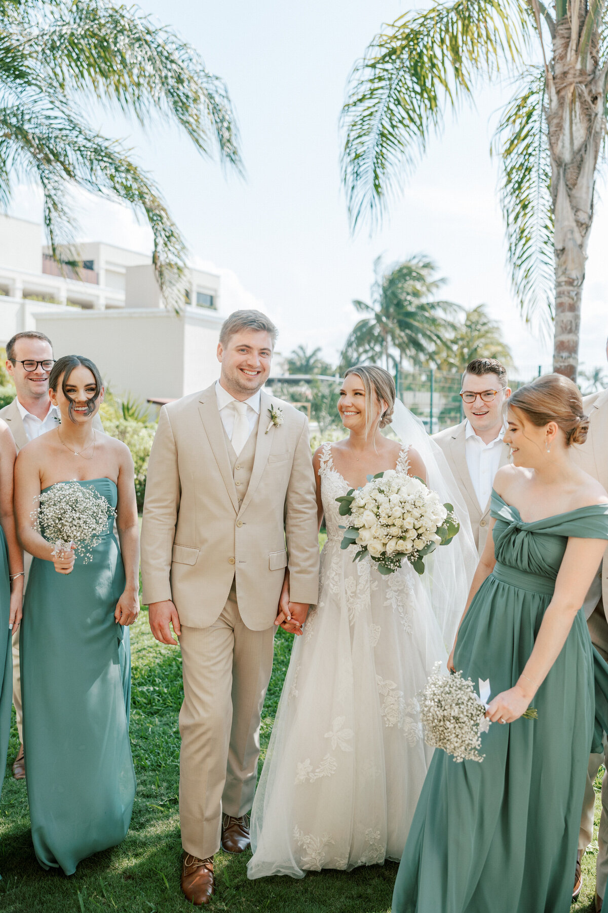 Bride and groom walk smiling with wedding party at Cancun resort, photographed by Philly photographer.