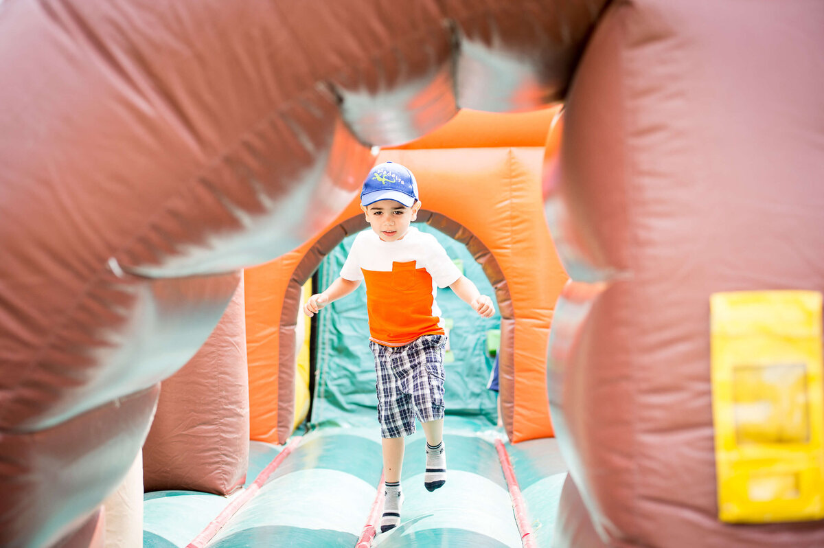 a little boy walking through a bouncy castle as part of a corporate children's event.  Captured by Ottawa Event Photographer JEMMAN Photography COMMERCIAL