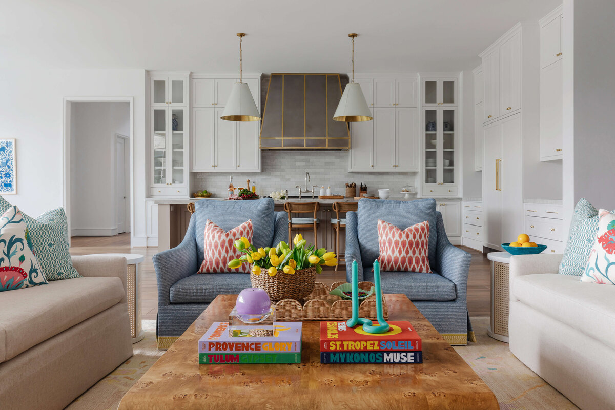 oyster creek studios memorial new build wooden coffe table with white cabinets and blue armchairs with red pillows