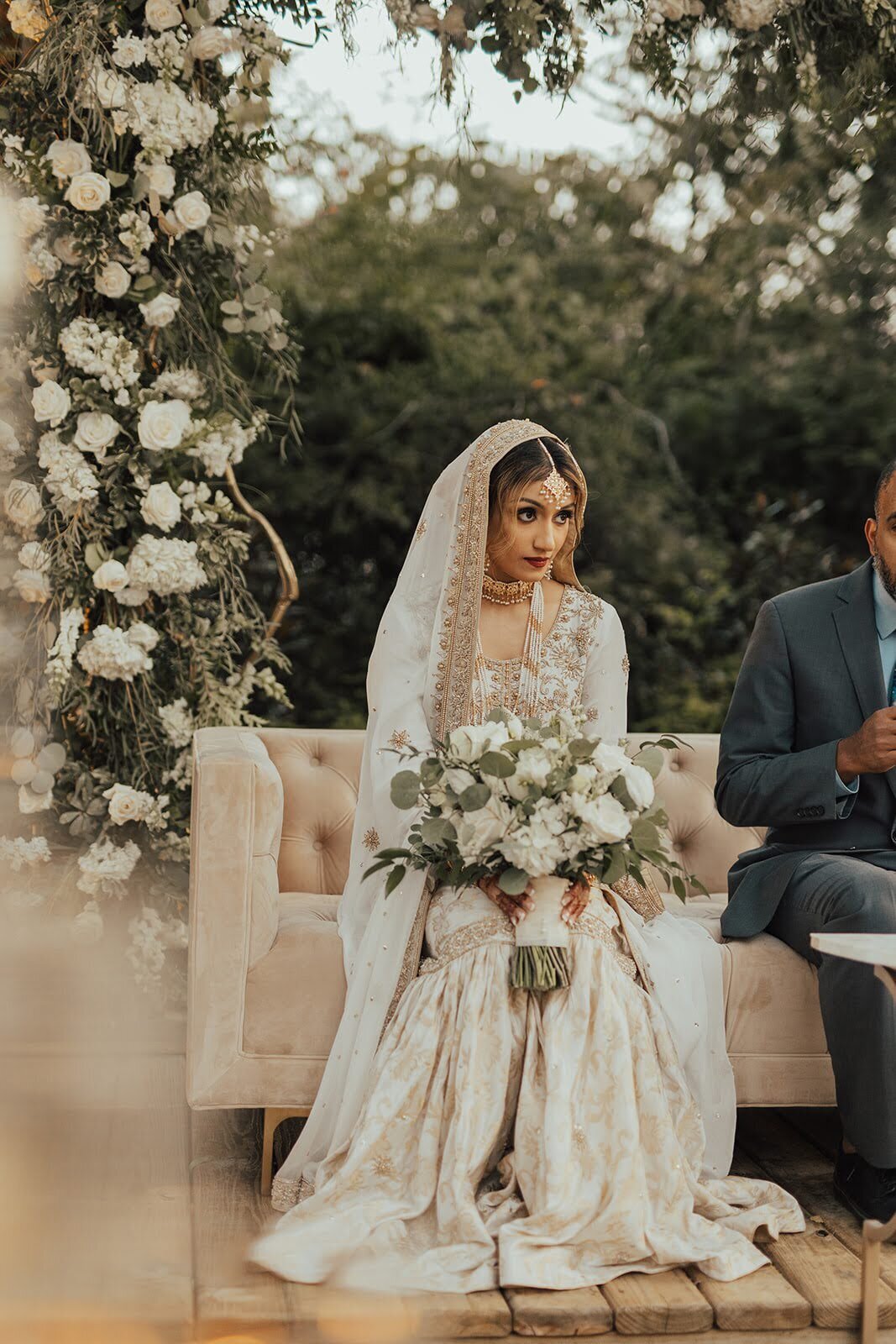 Bride during her wedding ceremony holding a white and greenery bouquet at the Bowery House and Gardens.