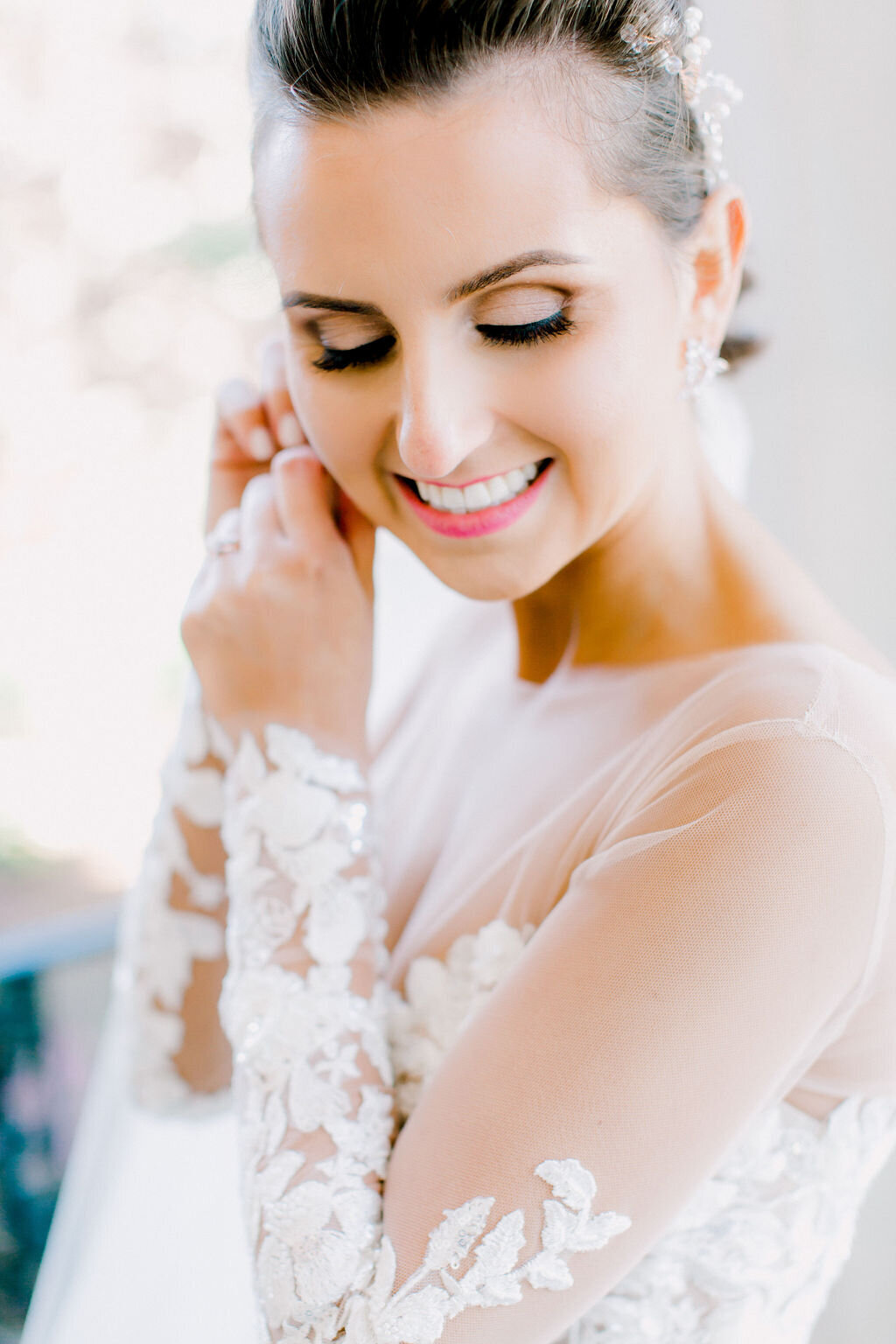 Intimate moment of the bride preparing for her big day, with focus on her thoughtful expression and beautiful details of her bridal attire