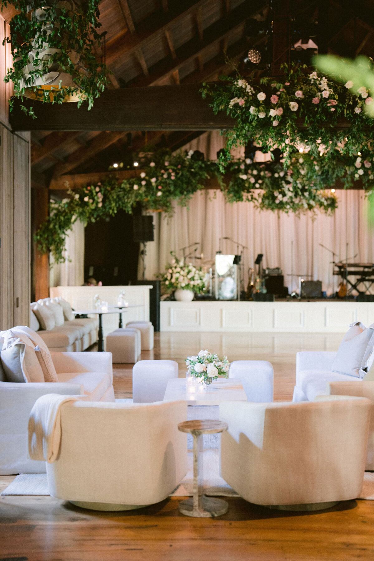 Lush garden inspired floral design growing in Bramble at Blackberry Farm for fall wedding reception. Growing floral installations on chandeliers and ceiling beams create garden setting for fall wedding reception. Timeless and elegant floral design in hues of white, cream, blush, and natural greens. Large trees with floral moments for outdoor wedding reception. Destination wedding at Blackberry Farm. Design by Rosemary & Finch Floral Design in Nashville, TN.