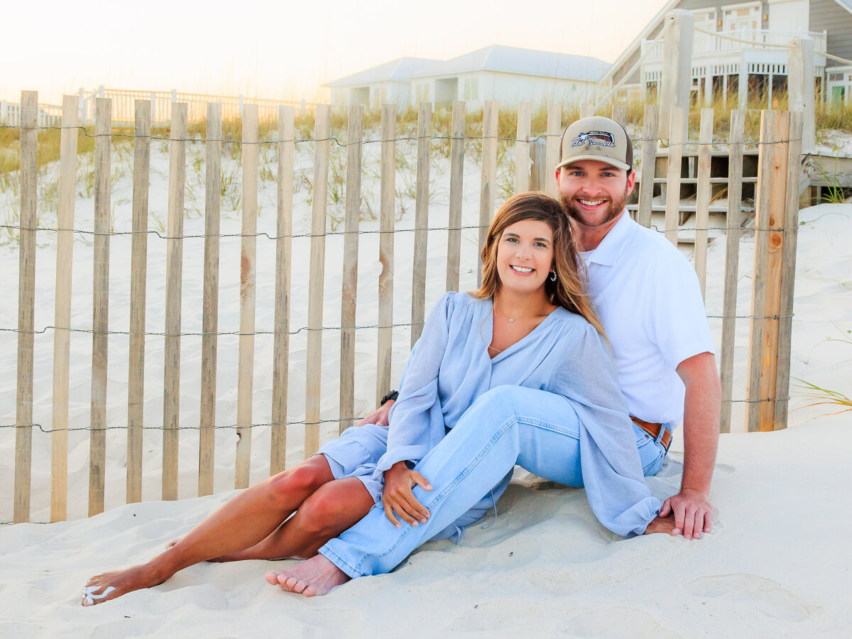 cute photo of couple on beach in front of fence