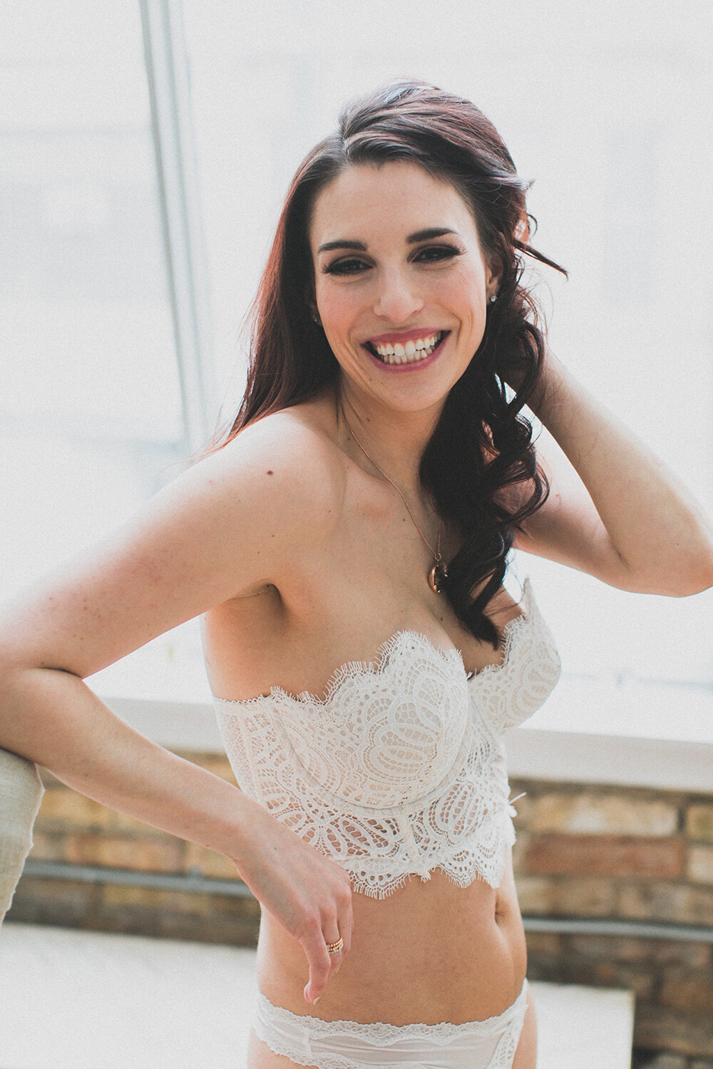 A woman smiles as she poses for a boudoir photo