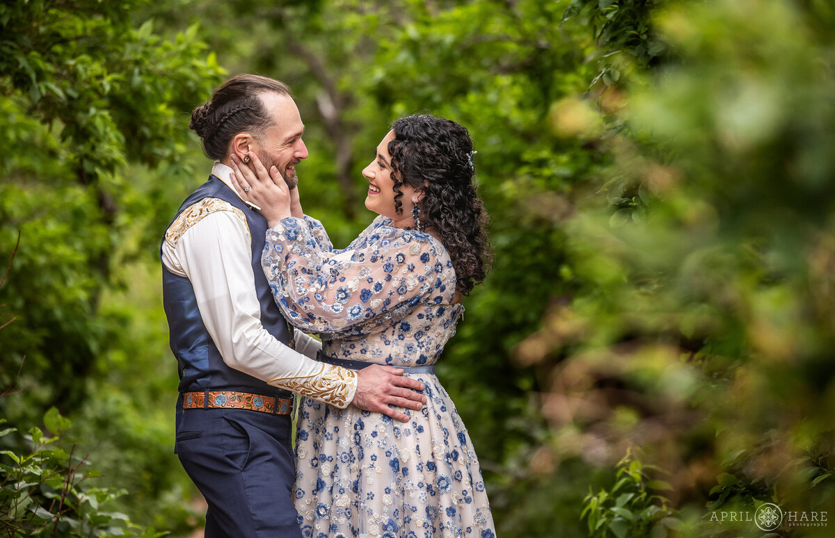 Couple gaze into each other's eyes with a greenery backdrop in Colorado