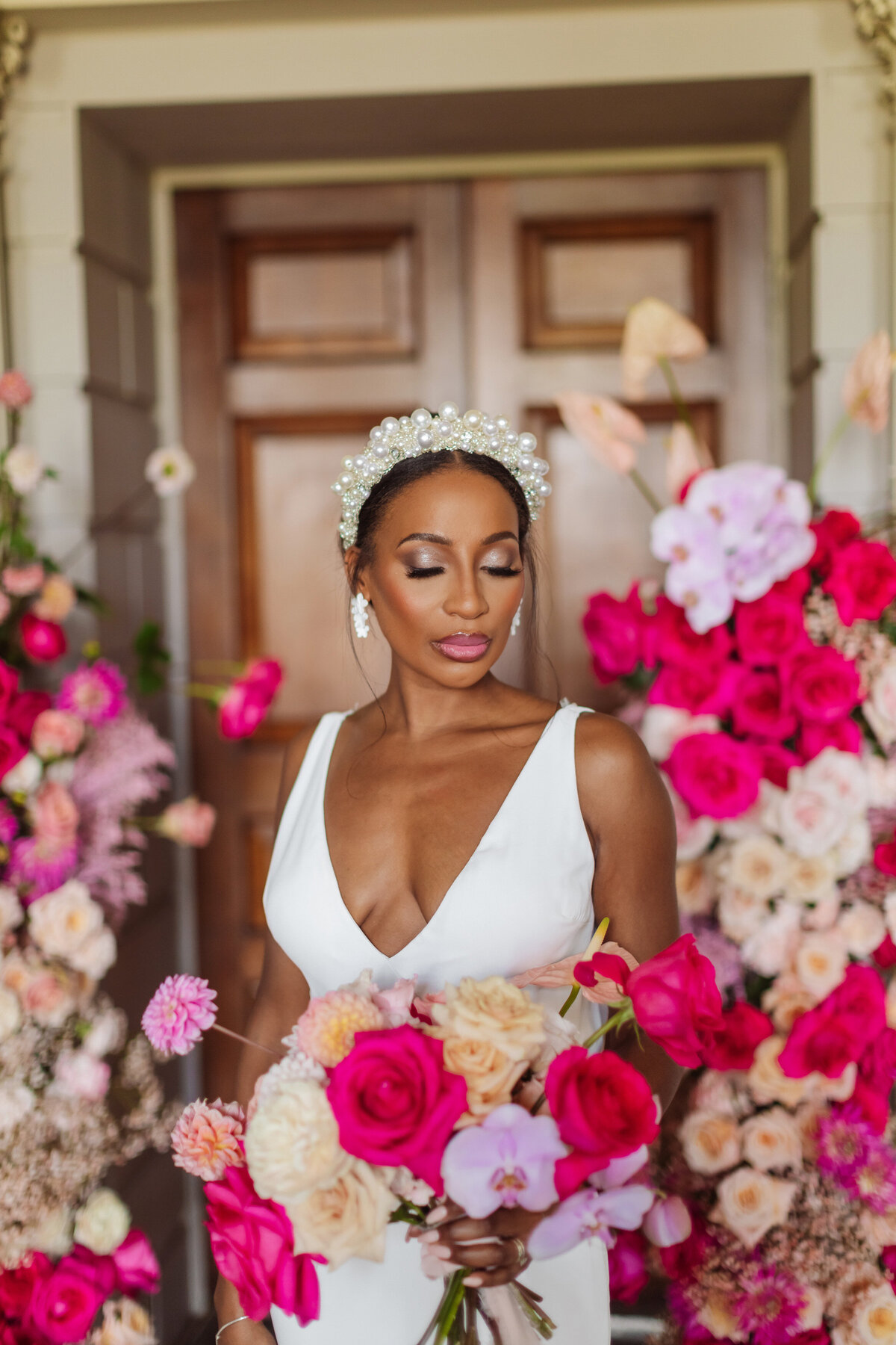 bride with hot pink wedding bouquet and floral arch